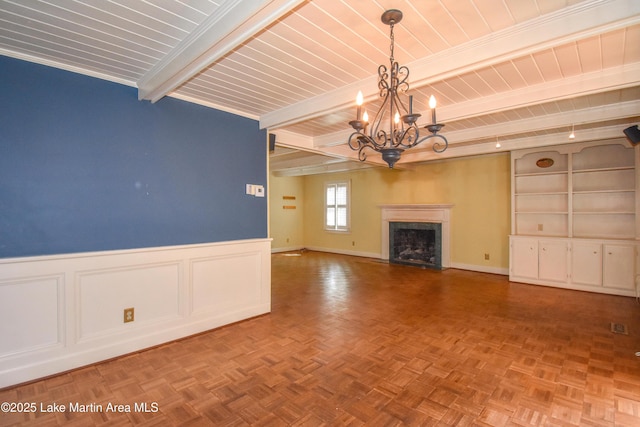 unfurnished living room featuring a high end fireplace, parquet flooring, beamed ceiling, and a chandelier