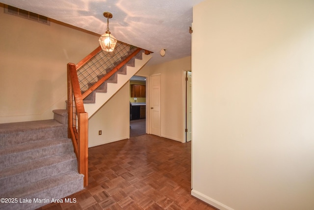 stairway featuring parquet floors and a textured ceiling