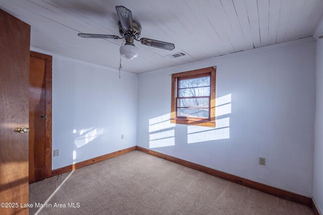 empty room with ornamental molding, carpet flooring, wood ceiling, and ceiling fan