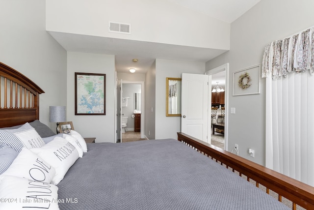 bedroom featuring connected bathroom, carpet, and a chandelier