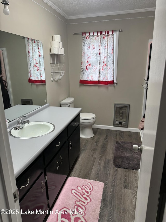 bathroom featuring heating unit, crown molding, a textured ceiling, vanity, and hardwood / wood-style flooring