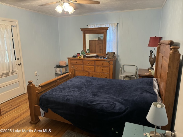 bedroom featuring ceiling fan, crown molding, a textured ceiling, and light wood-type flooring