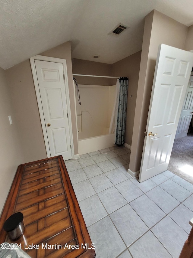 bathroom with tile patterned flooring, a textured ceiling, and shower / bathtub combination with curtain