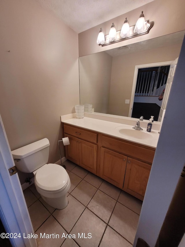 bathroom with tile patterned flooring, vanity, toilet, and a textured ceiling