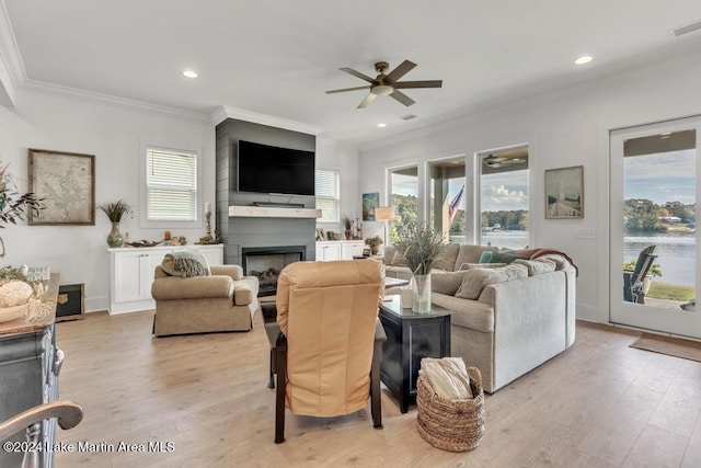 living room with ceiling fan, a large fireplace, light hardwood / wood-style floors, and ornamental molding