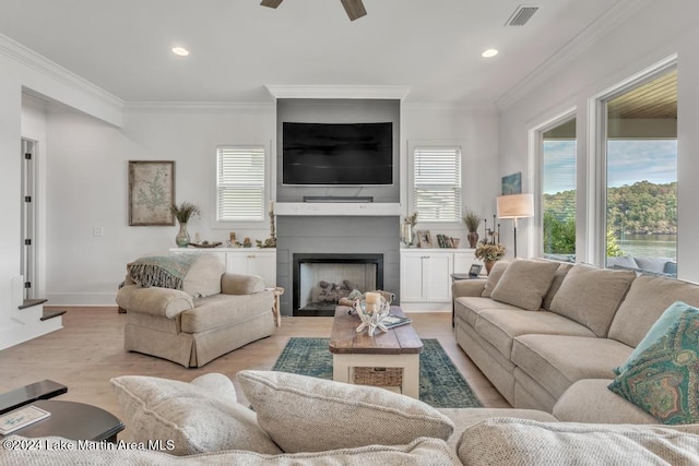 living room with ceiling fan, light hardwood / wood-style floors, crown molding, and a fireplace