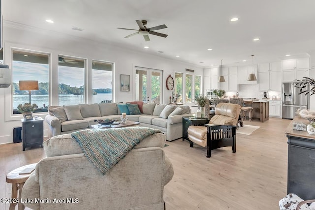 living room with french doors, light wood-type flooring, a water view, and ceiling fan