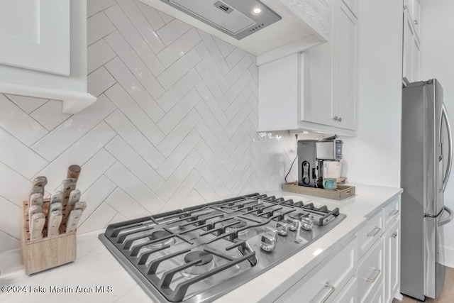 kitchen featuring white cabinets, appliances with stainless steel finishes, tasteful backsplash, and extractor fan