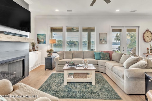 living room with french doors, light wood-type flooring, a water view, and crown molding