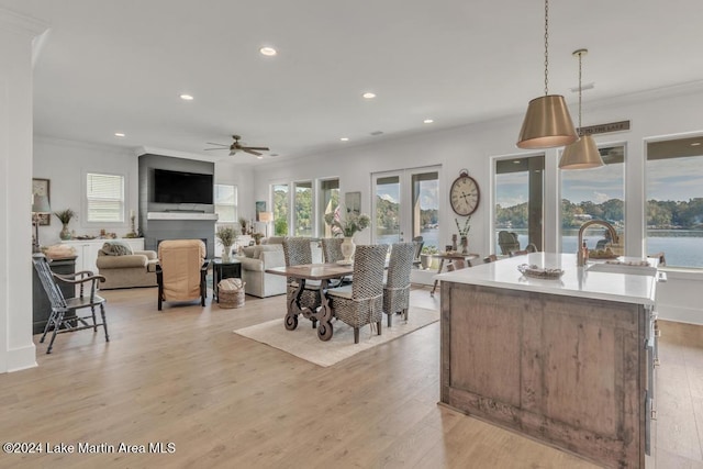 kitchen featuring a center island with sink, light hardwood / wood-style floors, decorative light fixtures, and ornamental molding