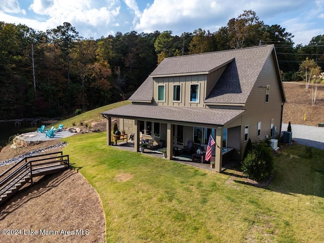 back of house with central air condition unit, a patio area, outdoor lounge area, and a lawn