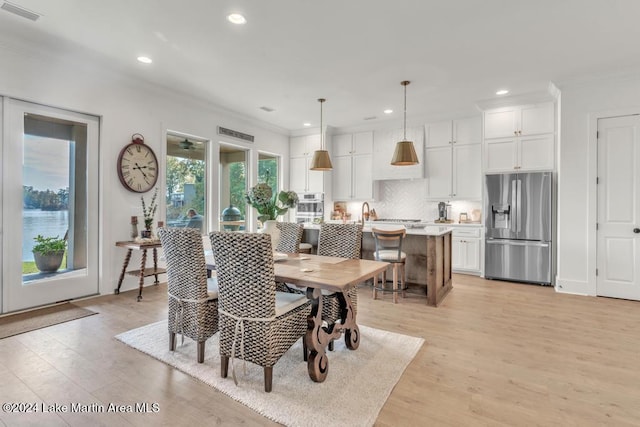 dining area with crown molding and light hardwood / wood-style flooring