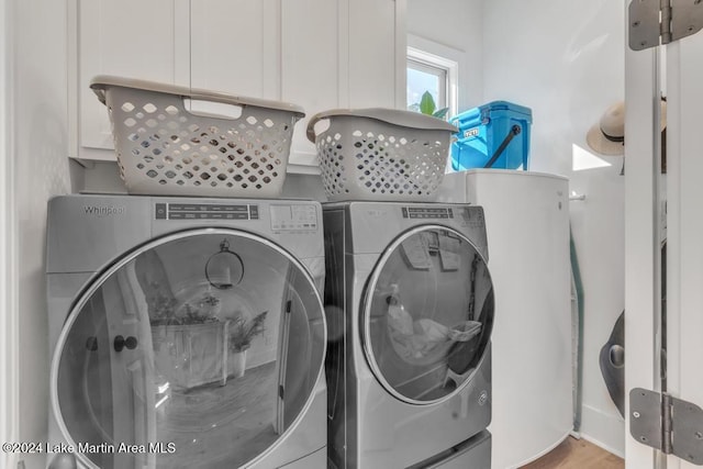 laundry area with washing machine and dryer and light hardwood / wood-style flooring