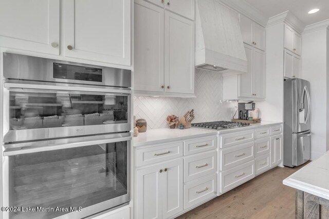 218 Williams Rd, Alexander City, AL 35010 - kitchen featuring stainless steel appliances, custom exhaust hood, light countertops, white cabinets, and tasteful backsplash