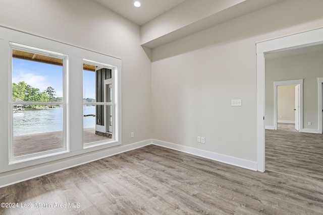 spare room with a water view and wood-type flooring