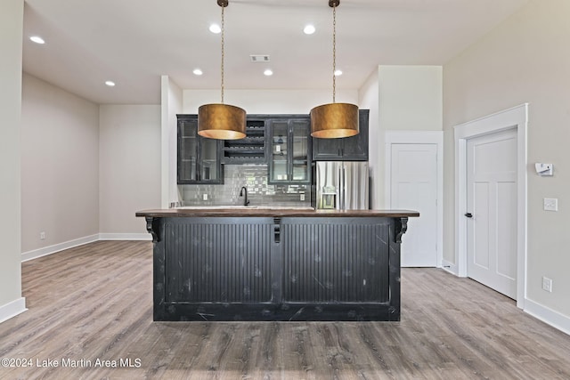 kitchen featuring stainless steel fridge with ice dispenser, a center island, hanging light fixtures, and wood-type flooring