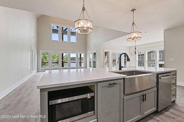 kitchen with gray cabinetry, sink, french doors, stainless steel appliances, and a notable chandelier