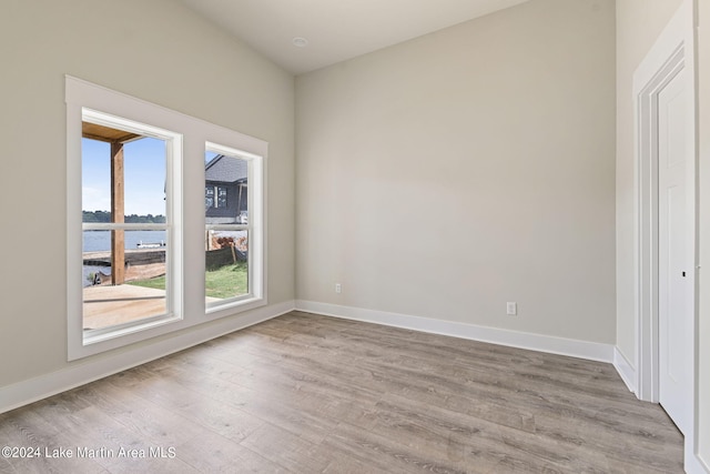 spare room with a water view, a wealth of natural light, and light hardwood / wood-style floors