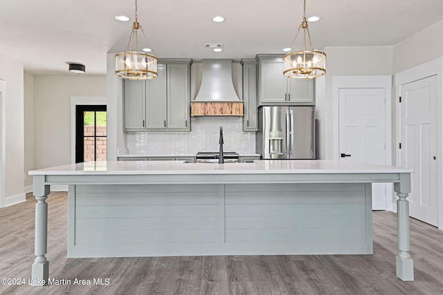 kitchen with decorative light fixtures, a spacious island, custom range hood, and stainless steel appliances