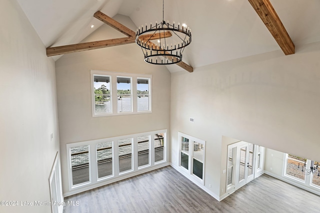 unfurnished living room featuring wood-type flooring, an inviting chandelier, high vaulted ceiling, and french doors