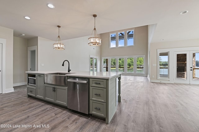 kitchen featuring sink, hanging light fixtures, a center island with sink, appliances with stainless steel finishes, and hardwood / wood-style flooring