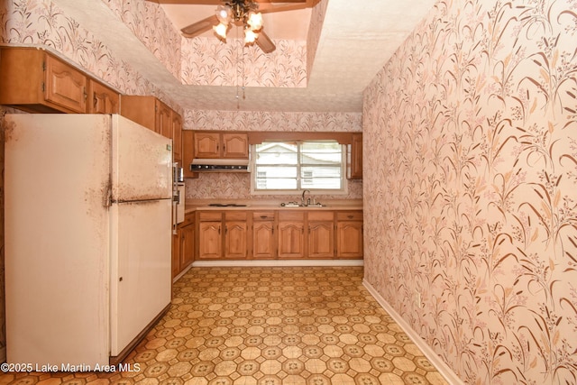 405 4th St, Tallassee, AL 36078 - kitchen featuring freestanding refrigerator, wallpapered walls, under cabinet range hood, a ceiling fan, and light countertops