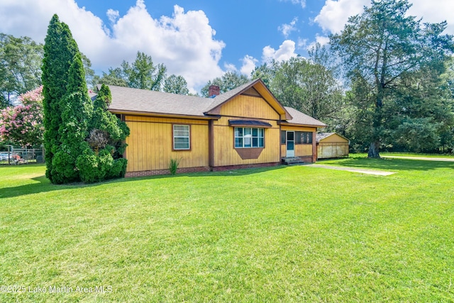 405 4th St, Tallassee, AL 36078 - view of front facade with a front lawn, a chimney, roof with shingles, and a detached garage