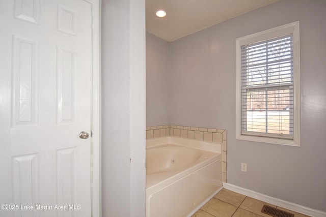 bathroom with a tub to relax in and tile patterned floors