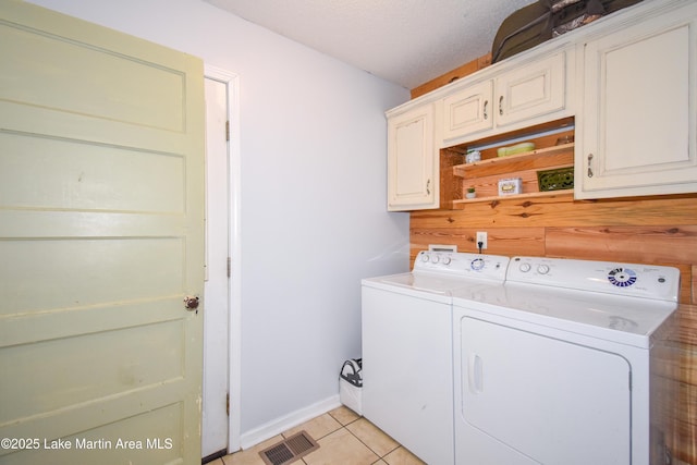 laundry room with cabinets, light tile patterned floors, a textured ceiling, and independent washer and dryer