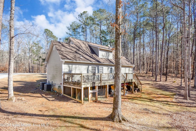 back of property featuring a garage, cooling unit, and a deck