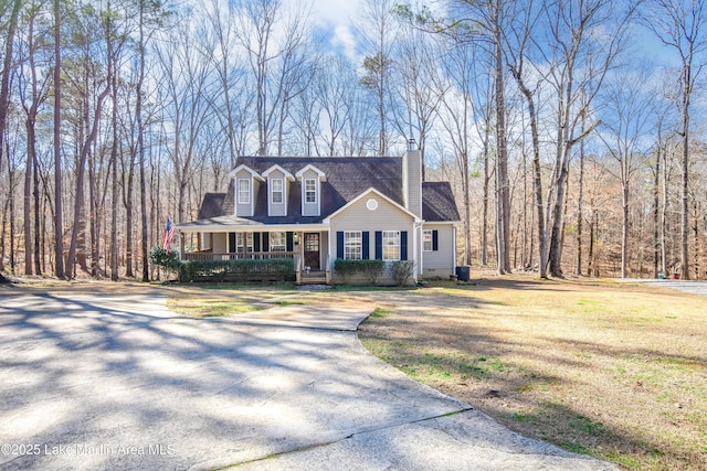 new england style home featuring a porch and a front lawn