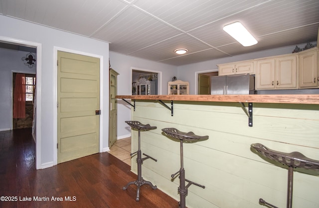 kitchen with hardwood / wood-style flooring, stainless steel fridge, and cream cabinetry