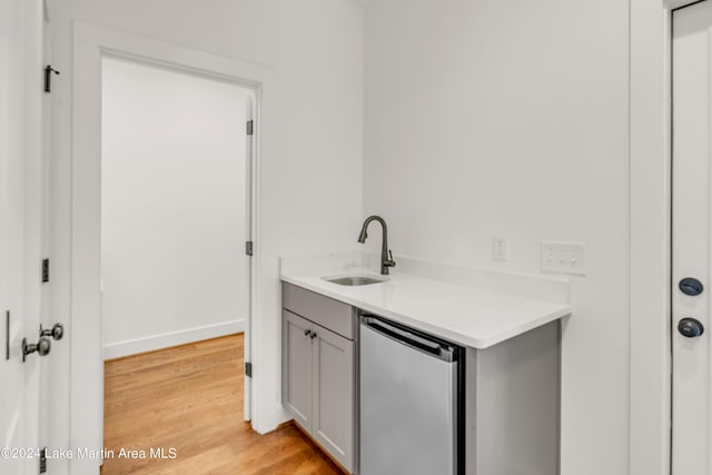 interior space with gray cabinetry, light hardwood / wood-style floors, sink, and stainless steel refrigerator