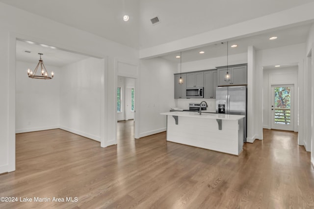 kitchen featuring gray cabinets, hardwood / wood-style flooring, stainless steel appliances, and a notable chandelier