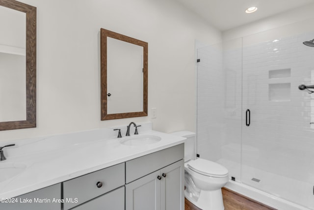 bathroom with hardwood / wood-style floors, vanity, toilet, and a shower with shower door