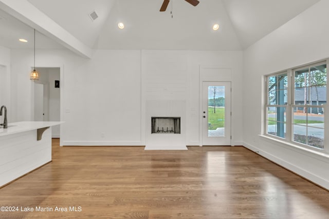 unfurnished living room with hardwood / wood-style flooring, high vaulted ceiling, ceiling fan, and sink