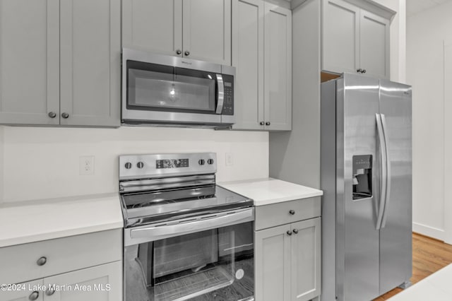 kitchen with hardwood / wood-style flooring, gray cabinets, and stainless steel appliances