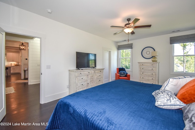 bedroom featuring dark hardwood / wood-style flooring and ceiling fan with notable chandelier