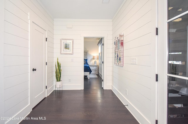 hallway with dark hardwood / wood-style flooring, crown molding, and wood walls