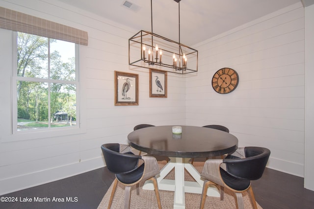 dining room with wood-type flooring, wooden walls, and a healthy amount of sunlight