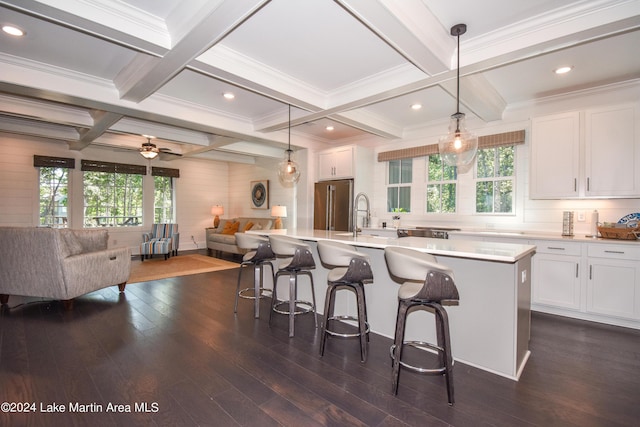 kitchen with white cabinets, decorative light fixtures, a kitchen island with sink, and dark wood-type flooring