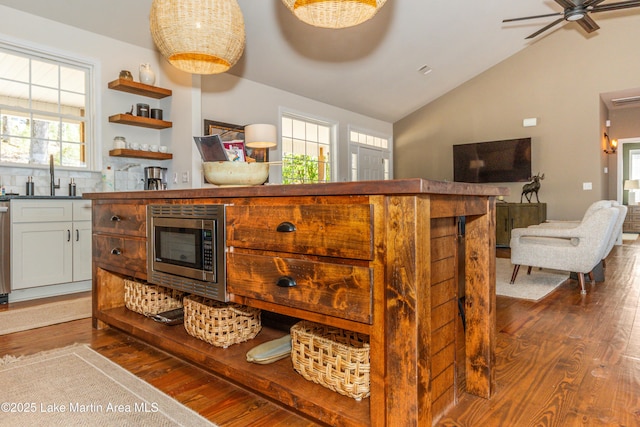 kitchen featuring a sink, stainless steel microwave, lofted ceiling, and dark wood-type flooring