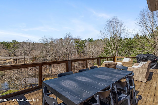 deck with grilling area, outdoor dining space, and a wooded view