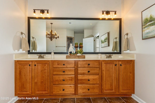 full bathroom with double vanity, a chandelier, baseboards, and a sink