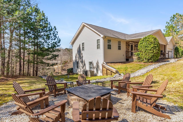 rear view of house featuring an attached garage, a yard, central AC, and an outdoor fire pit