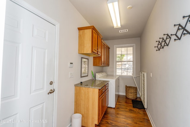 clothes washing area with visible vents, baseboards, dark wood finished floors, cabinet space, and independent washer and dryer