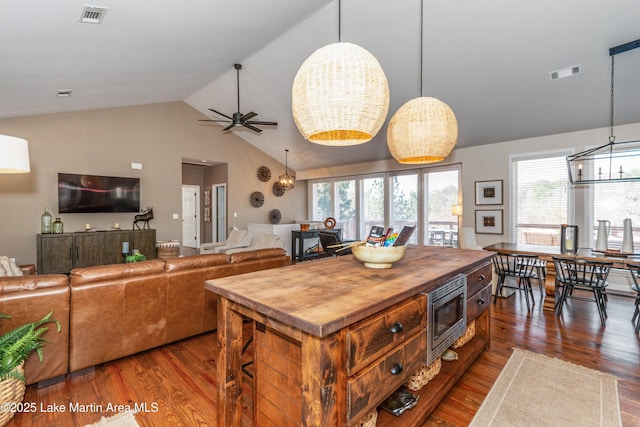 kitchen with visible vents, stainless steel microwave, wood counters, and dark wood-style flooring