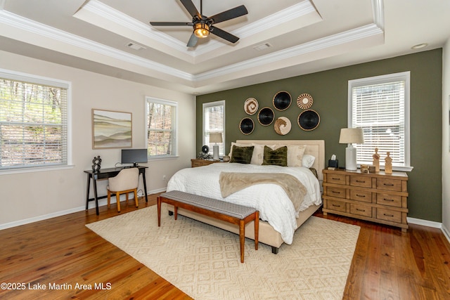 bedroom featuring multiple windows, a raised ceiling, and hardwood / wood-style flooring