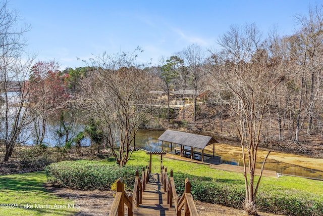 view of community featuring a yard, boat lift, and a boat dock