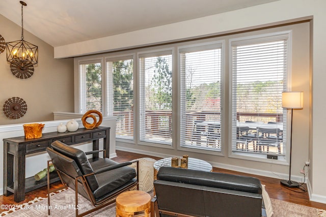 interior space with a chandelier, a healthy amount of sunlight, lofted ceiling, and wood finished floors